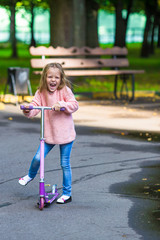 Adorable little girl have fun on the scooter outdoor