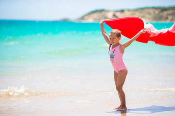 Naklejka na ściany i meble Little girl with beach towel during tropical vacation