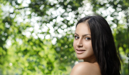 Naklejka premium Portrait of a young brunette on nature background