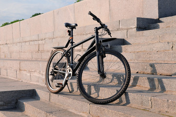 Fototapeta na wymiar Black bicycle stands on the stone steps