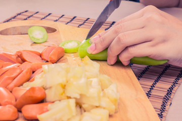Preparing sausage and vegetables woman hands vintage tone.