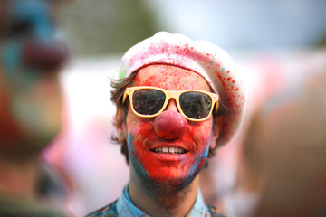 Portrait of a smiling clown in sunglasses ; color festival celebration