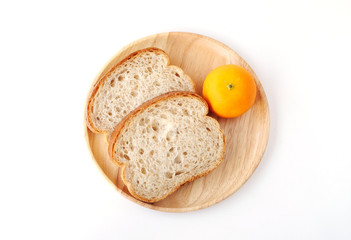 Whole wheat bread and orange on wooden plate isolated on white background