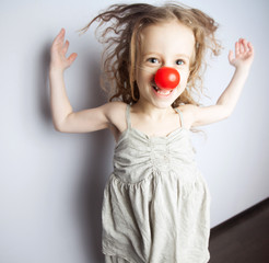 a little girl wearing a clown nose