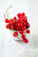 red currants in a bowl on wooden surface