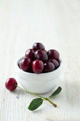 cherries in a bowl on wooden surface