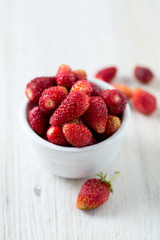 wild strawberries in a bowl on wooden surface
