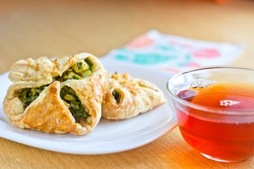 Fresh baked homemade puff pastry cakes with fresh strong black tea in glass cup