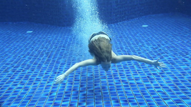 Girl swimming underwater in outdoor swimming pool
