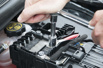 Mani che riparano un motore di automobile con una chiave