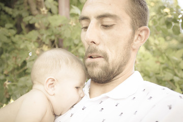 Bebe en brazos de su padre jugando en el parque. Primer plano de un padre jugando con su bebe desnudo en pañal. Bebe feliz.