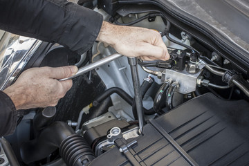 Mani che riparano un motore di automobile con una chiave