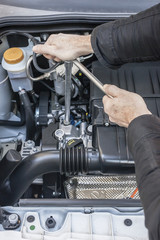 Mani che riparano un motore di automobile con una chiave