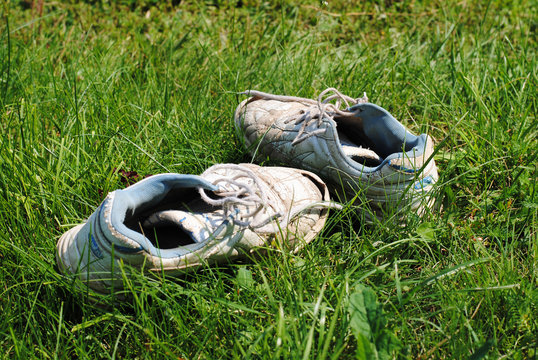 Old dirty sport shoes on grass