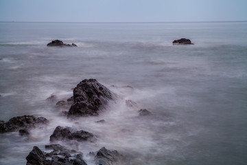 waves hitting the shore and rocks on the beach with slow shutter