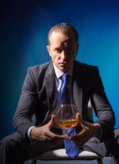 A man in a suit with a glass of spirits