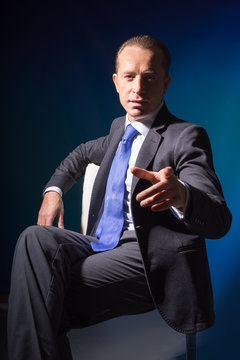 A man in a business suit extended his arm forward with the index finger