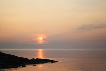 Ladoga lake at sunset. Calm water. A boat on the horizon.
