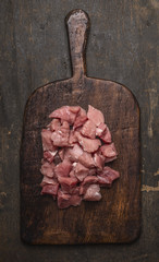 raw stew on the old board on a dark textured background, top view