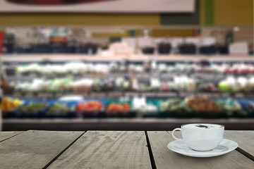 Defocus and blur image of supermarket with coffee on terrace wood background