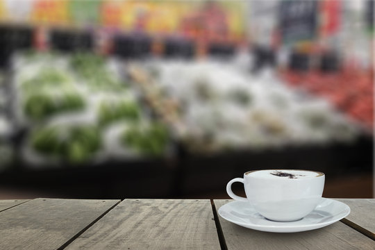 Defocus and blur image of supermarket with coffee on terrace wood background