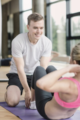 Fototapeta na wymiar smiling woman with male trainer exercising in gym