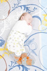 Newborn baby in pyjamas and woolen socks sleeping
