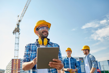 builder in hardhat with tablet pc at construction