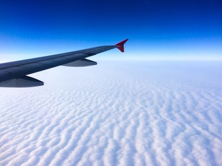 Wing of the plane with cloudy sky on background