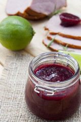 Home made organic cherry jam confiture, smoked meat, rosemary and lime on a wooden table