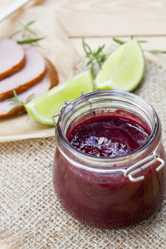 Home made organic cherry jam confiture, smoked meat, rosemary and lime on a wooden table