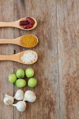 Herbs and spices in wooden spoons on wooden background