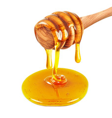 Honey dripping from a wooden honey dipper on white background