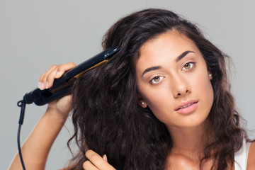 Obraz premium Woman doing hairstyle with hair straightener