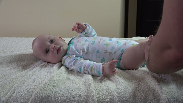 Masseur therapist massage happy smiling infant baby body leg on table at work. Healthy lifestyle. Zoom out shot. 4K UHD video clip.
