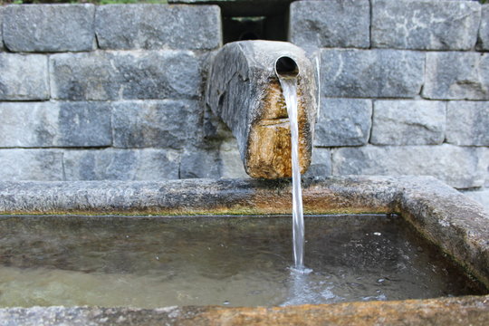 Wasser fließt aus einem Rohr in einen Brunnen