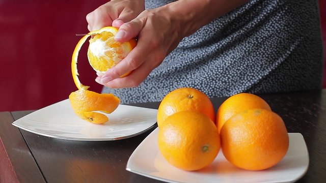 Young housewife peels oranges for fresh juice. Cooking in the kitchen.