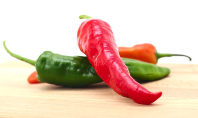 Colorful pepper pods closeup on wooden surface, white background, local soft focus, shallow DOF.  