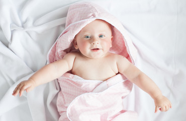 happy baby with a towel after the shower in bed at home