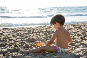 Bambina con capelli corti e castani che gioca in riva al mare