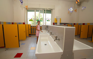 smiling girl washing her hands in the bathroom of the school