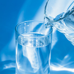 Glass of water with a jug on a blue background