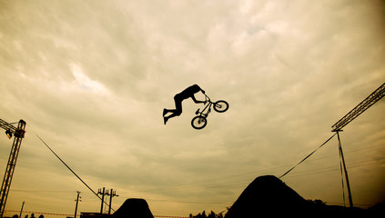 Silhouette of a man doing a jump with a bmx bike against sunset