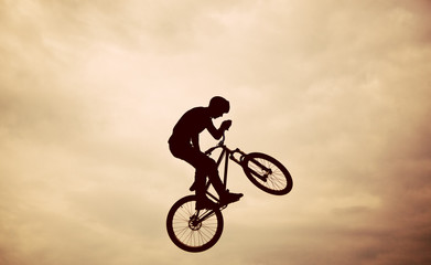 Silhouette of a man doing a jump with a bmx bike against sunset