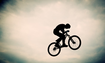 Fototapeta na wymiar Silhouette of a man doing a jump with a bmx bike against sunset