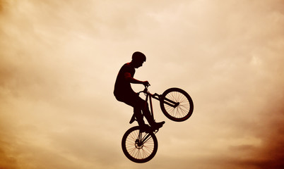 Silhouette of a man doing a jump with a bmx bike against sunset