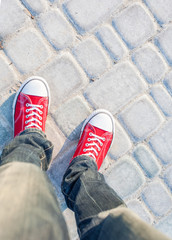 young man feet in red sneakers on cobbled road