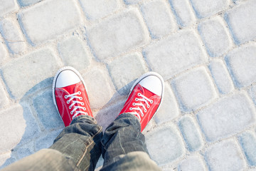 young man feet in red sneakers on cobbled road