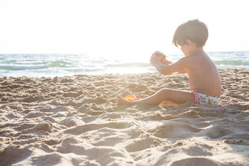 Bambina che gioca da sola sulla riva del mare in controluce