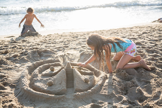 Due bambini che costruiscono un castello di sabbia in controluce